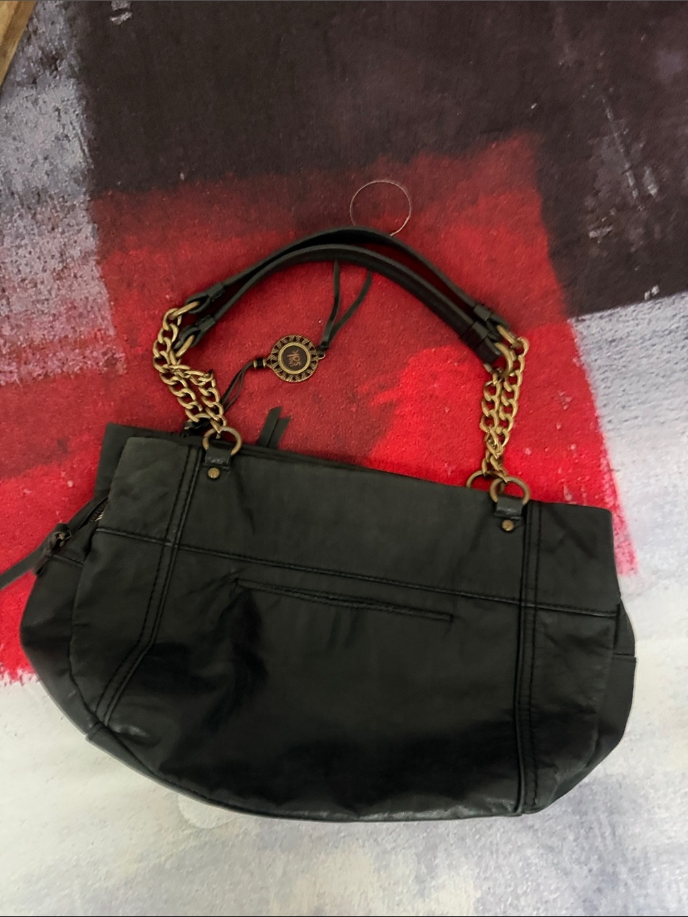 The Sak Black Shoulder Bag with Gold Chain Handles and Medallion